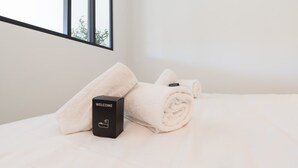 A neatly made bed with a rolled white towel and a black welcome box. - Le Cosy Azuréen - Welkeys (Antibes)