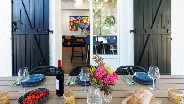 A dining table set with plates, glasses, a bottle, and a loaf of bread. - Villa Atlantide - Welkeys (Moliets-et-Maa)