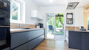 A modern kitchen with a wooden countertop, built-in cabinets, and a large window. - Villa Atlantide - Welkeys (Moliets-et-Maa)