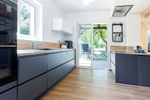 Une cuisine moderne avec un plan de travail en bois, des placards intégrés et une grande fenêtre.