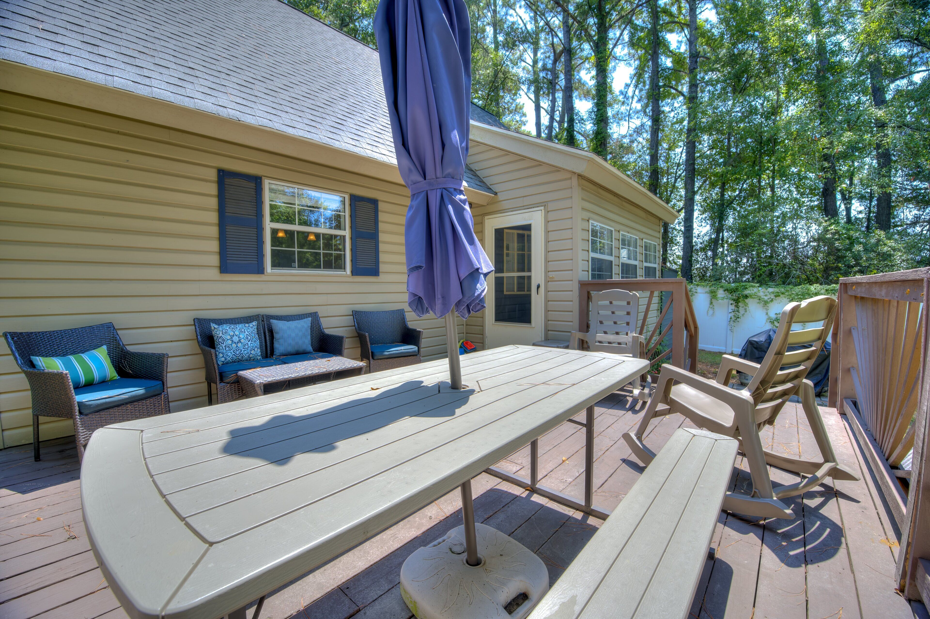 Une terrasse extérieure avec une table de pique-nique, des chaises et un parasol.