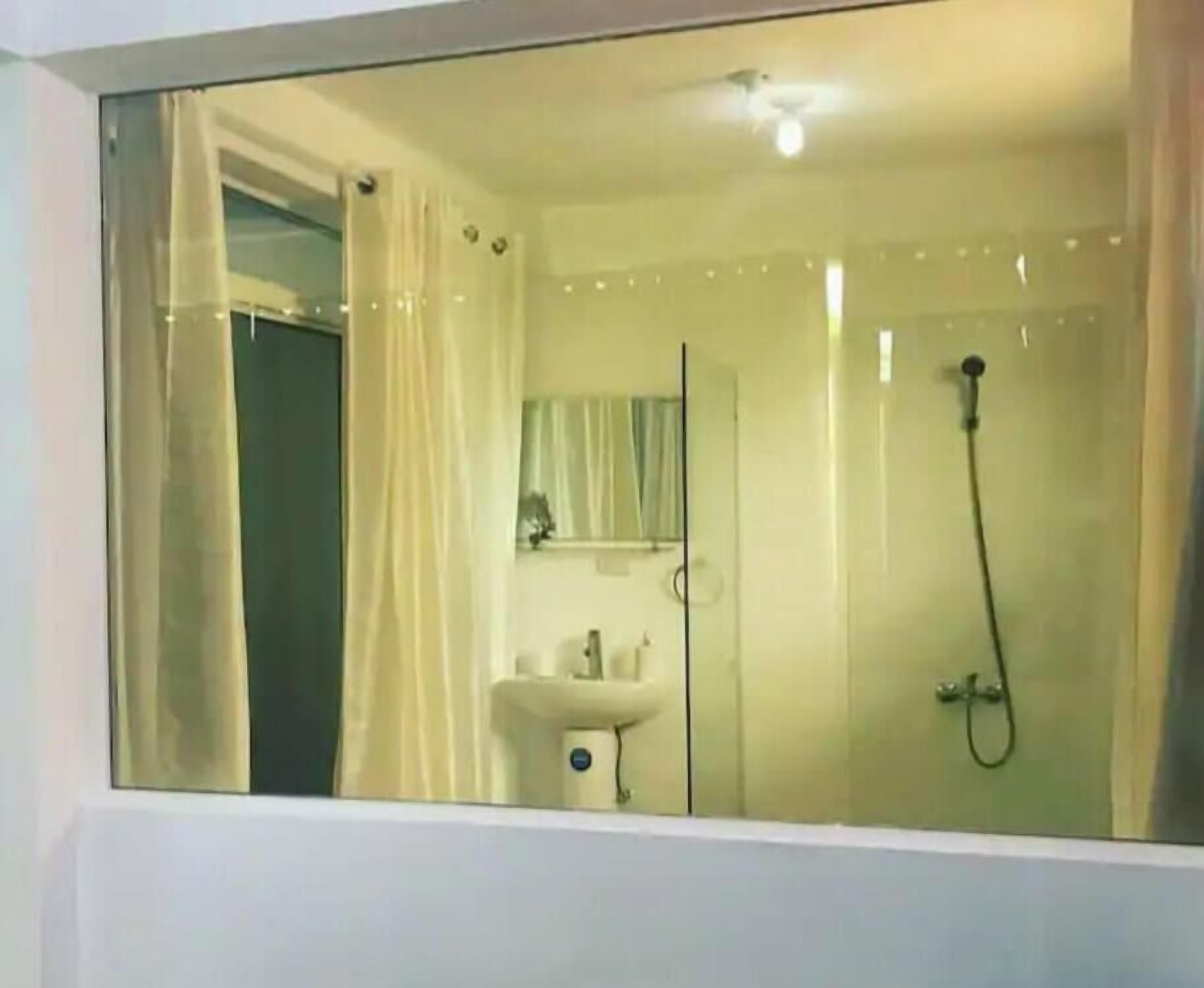 Baño con cabina de ducha de vidrio, lavamanos y espejo.