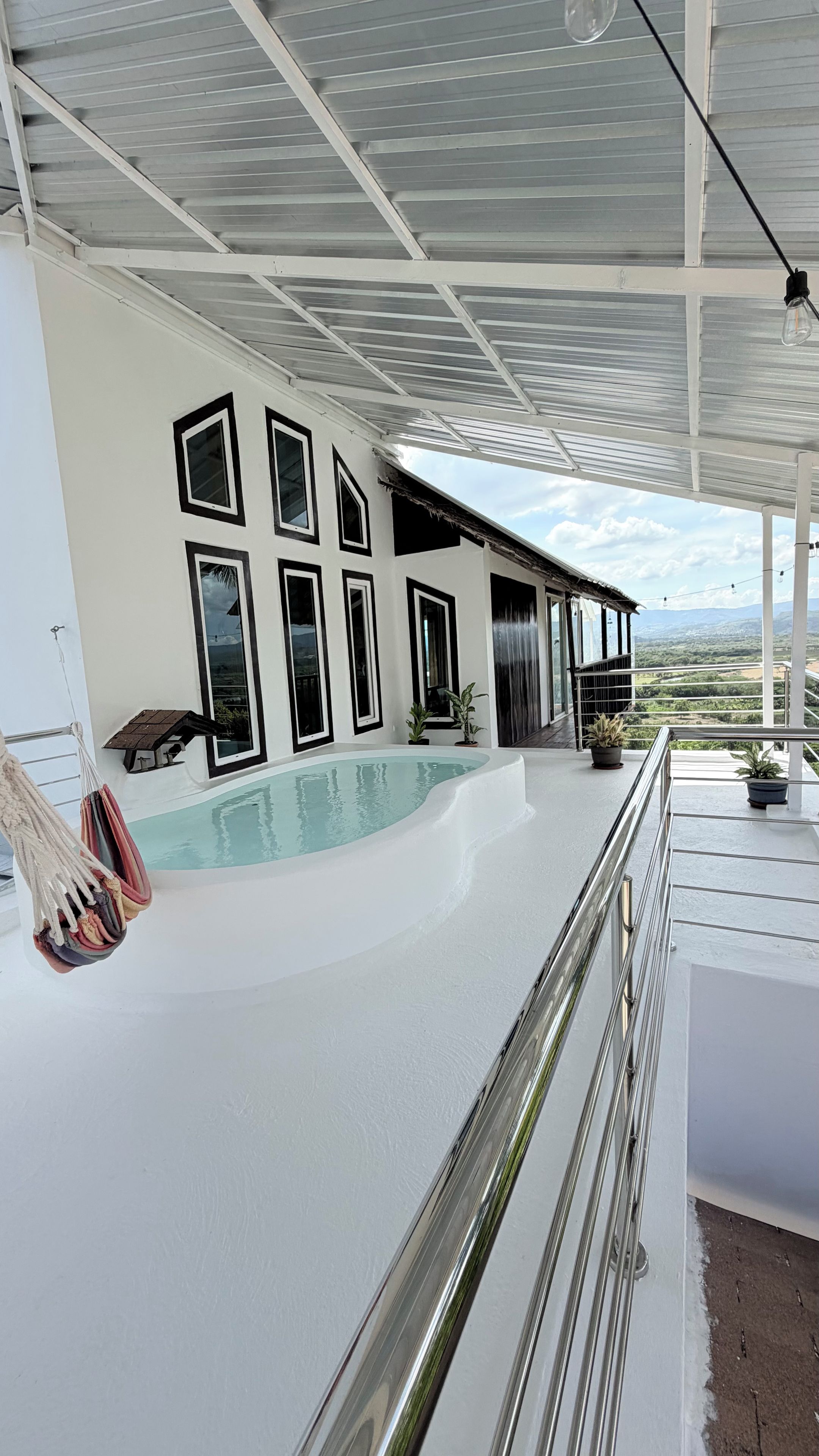 A modern pool area with a glass ceiling, multiple windows, and a view of the landscape.