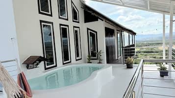 A modern pool area with a glass ceiling, multiple windows, and a view of the landscape.