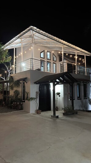 A two-story building with a covered balcony and string lights. - Villas André  (Luperon)