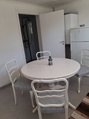 A round dining table with four chairs, a white cabinet, and a water heater.