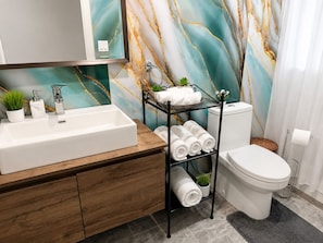 A bathroom with a white sink, a mirror, a toilet, and a towel rack. - Private beautiful Suite in Bungalow (Brossard)