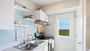 Une cuisine de taille réduite avec une fenêtre donnant sur l’extérieur, une cuisinière et un évier.