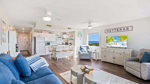 Un salon moderne avec un canapé, un téléviseur et une vue sur la plage.