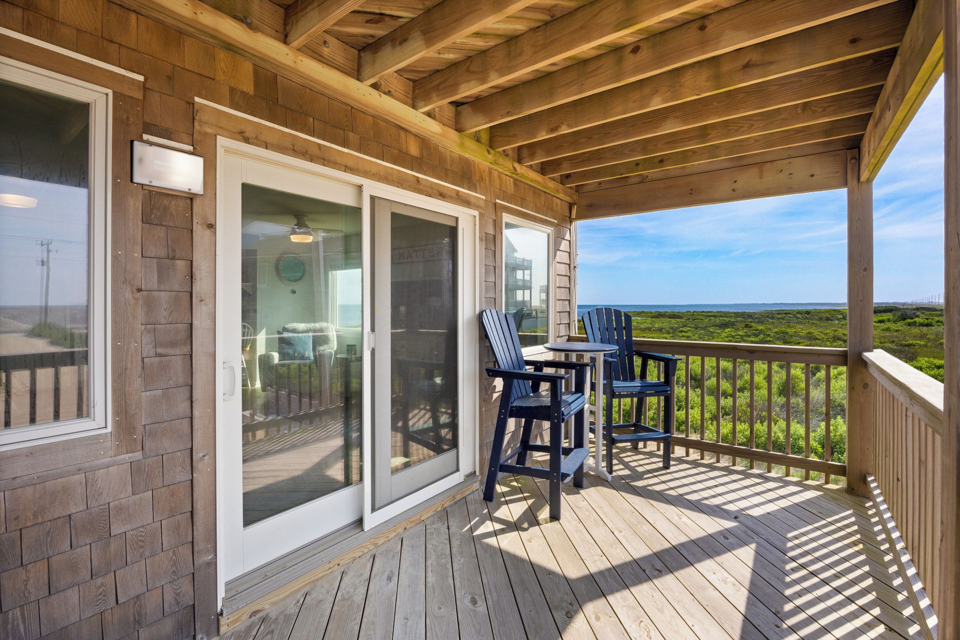 A covered outdoor area with a wooden deck, a table, and chairs.