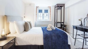 Hotellihuone, jossa on sänky, työpöytä, tuoli, lamppu ja ikkuna, josta on näkymä.