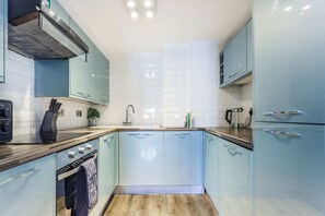 Eine moderne Küche mit hellblauen Schränken, einer Holz Arbeitsplatte, einem eingebauten Ofen und einer Edelstahl-Dunstabzugshaube.