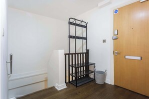 Ein Zimmer mit einer Holztür, einem Metallgestell und einem Mülleimer.
