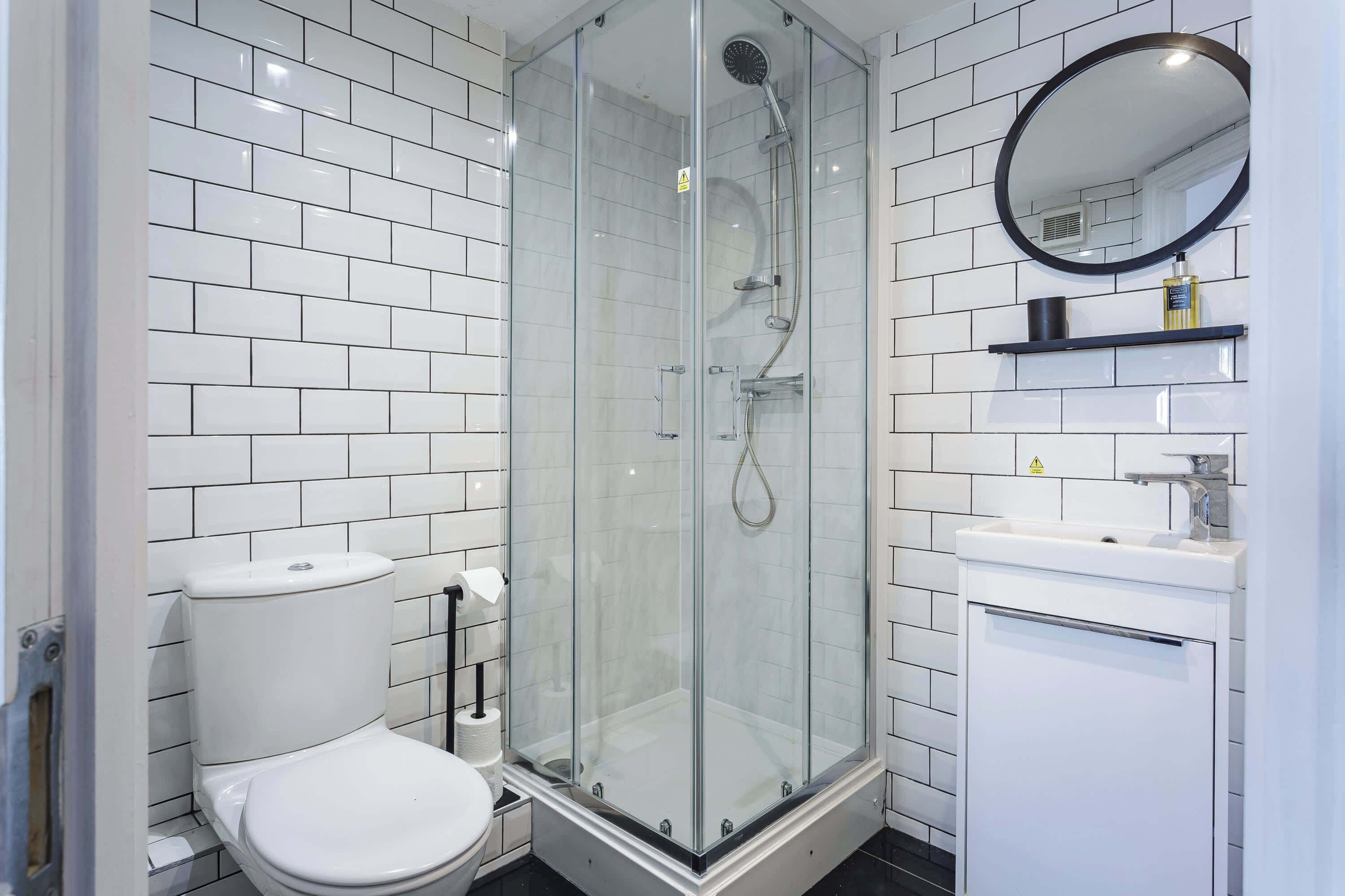 Une salle de bain moderne avec une douche à parois de verre, des toilettes, un lavabo et un miroir.