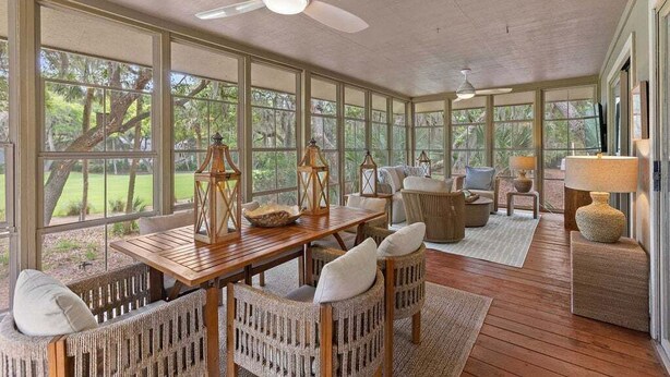 A spacious covered patio with a wooden table, wicker chairs, and a sofa. - 3BR golf-course cottage on Seabrook Island w/screened porch "Serene Seahorse"-no pets (Seabrook Island)
