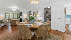 A dining area with a round table, wicker chairs, and a hanging light fixture. - 3BR golf-course cottage on Seabrook Island w/screened porch "Serene Seahorse"-no pets (Seabrook Island)