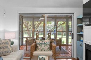 A living room with a sofa, a chair, a table, and a fireplace. - 3BR golf-course cottage on Seabrook Island w/screened porch "Serene Seahorse"-no pets (Seabrook Island)