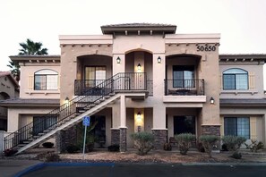 Un edificio de varios pisos con fachada color beige, numerado 50650, que presenta una escalera central, balcones y una entrada accesible para sillas de ruedas.