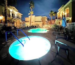 A swimming pool area with lounge chairs and a building in the background. - La Quinta Workcation Condo · Fast WiFi & Pool (La Quinta)