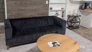 A modern living room with a black sofa, a wooden coffee table, and a white cabinet.
