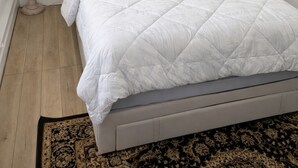 A bedroom with a bed, a floor lamp, and a patterned rug.