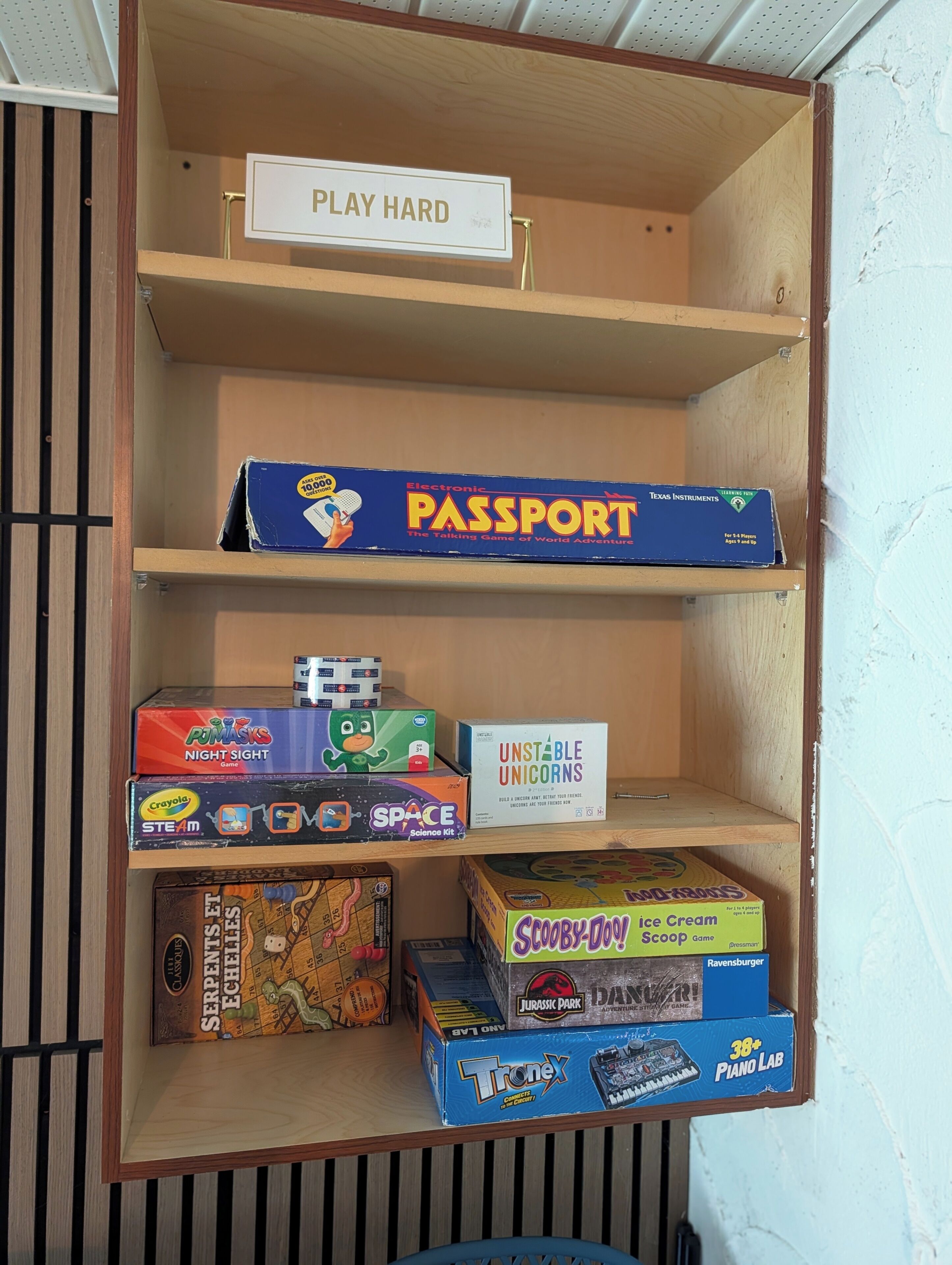 A shelf with various board games including 'Passport' and 'Unstable Unicorns'.