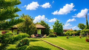 Uma casa com varanda, gramado e jardim.