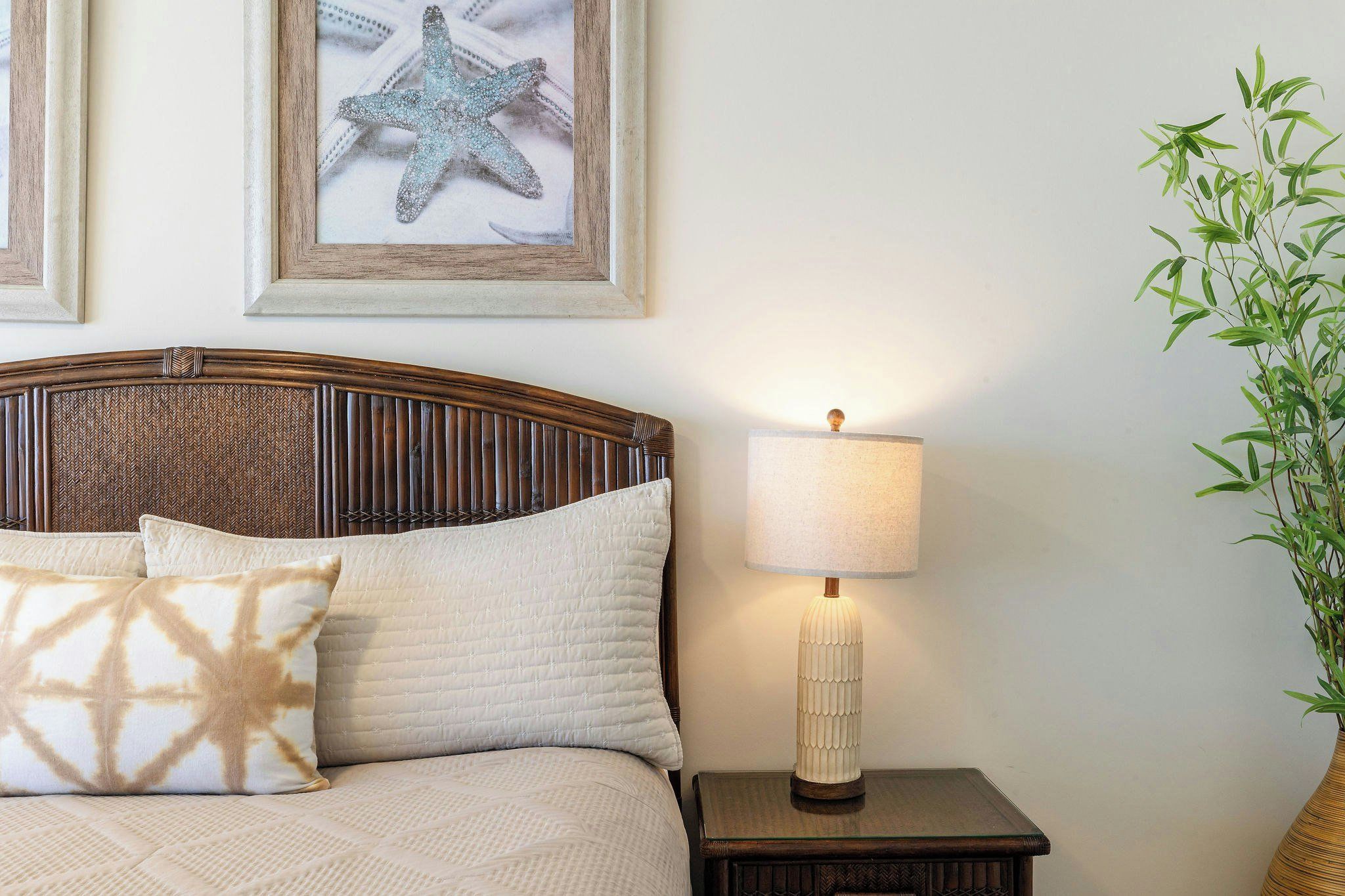 A bed with a headboard, pillows, a bedside lamp, and a framed starfish decoration on the wall.