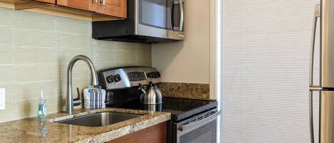 Una cocina con electrodomésticos de acero inoxidable, encimera de granito y armarios de madera.