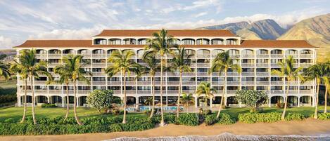 A multi-story hotel with a pool, palm trees, and a beach view.