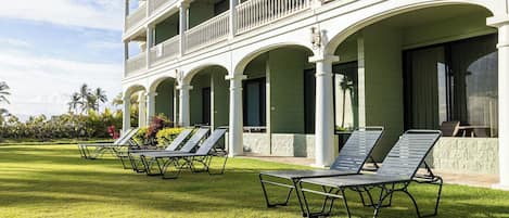 A hotel with a multi-story building, outdoor seating area with lounge chairs, and a well-maintained lawn.