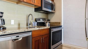 A kitchen with stainless steel appliances, wooden cabinets, and a granite countertop.