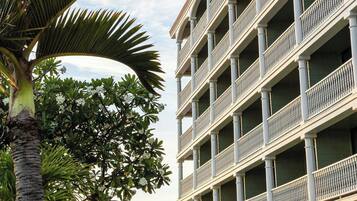 A multi-story hotel with balconies and a palm tree in the foreground.