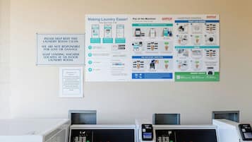 Un lavadero con instrucciones para usar lavadora y secadora de carga frontal, una aplicación de pago móvil y una máquina expendedora de jabón.