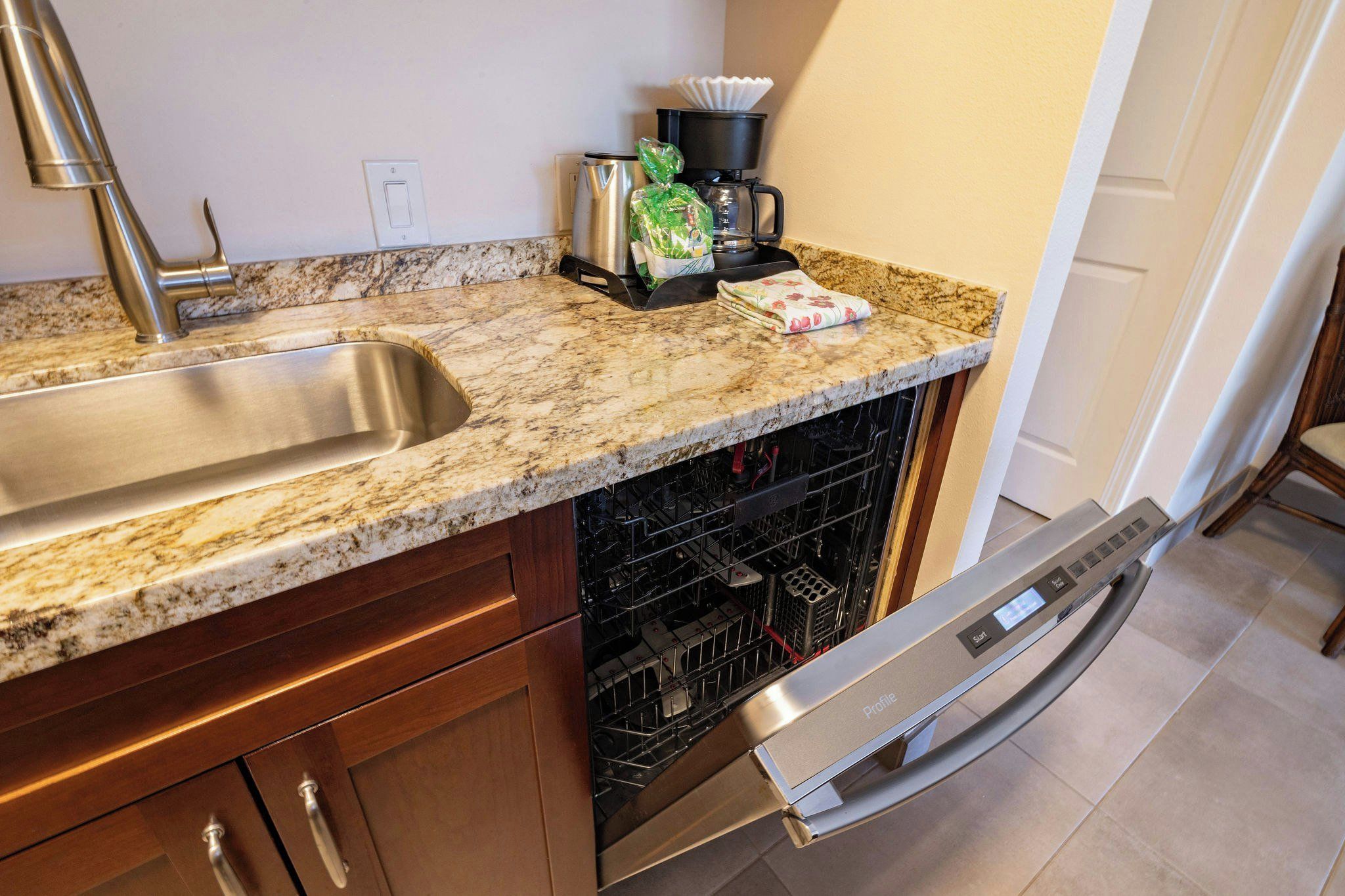 A kitchen with a stainless steel sink, a coffee maker, and a dishwasher.