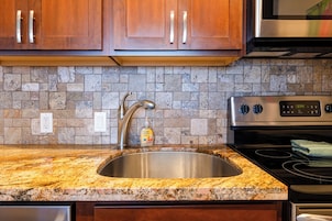 Una cocina con encimeras de granito, electrodomésticos de acero inoxidable y salpicadero de piedra.