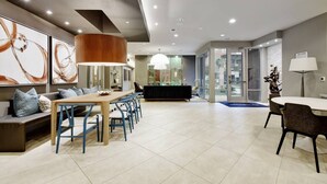 A modern hotel lobby with a dining area, a reception desk, and a large window. - Luxury Apartment with Fast Wi-Fi  and Free Parking (San Antonio)