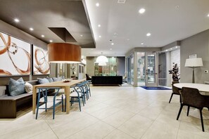 A modern hotel lobby with a dining area, a reception desk, and a large window. - Luxury Apartment with Fast Wi-Fi  and Free Parking (San Antonio)