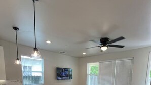 A modern living room with a marble kitchen island, a brown leather sofa, and a ceiling fan. - Minutes to midtown-New Build Urban Retreat (Sacramento)