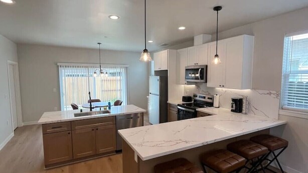 A modern kitchen with a central island, bar stools, and pendant lighting. - Minutes to midtown-New Build Urban Retreat (Sacramento)