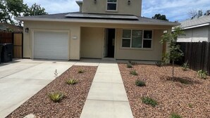 A single-story house with a garage, a front entrance, and a small front yard with gravel and plants. - Minutes to midtown-New Build Urban Retreat (Sacramento)