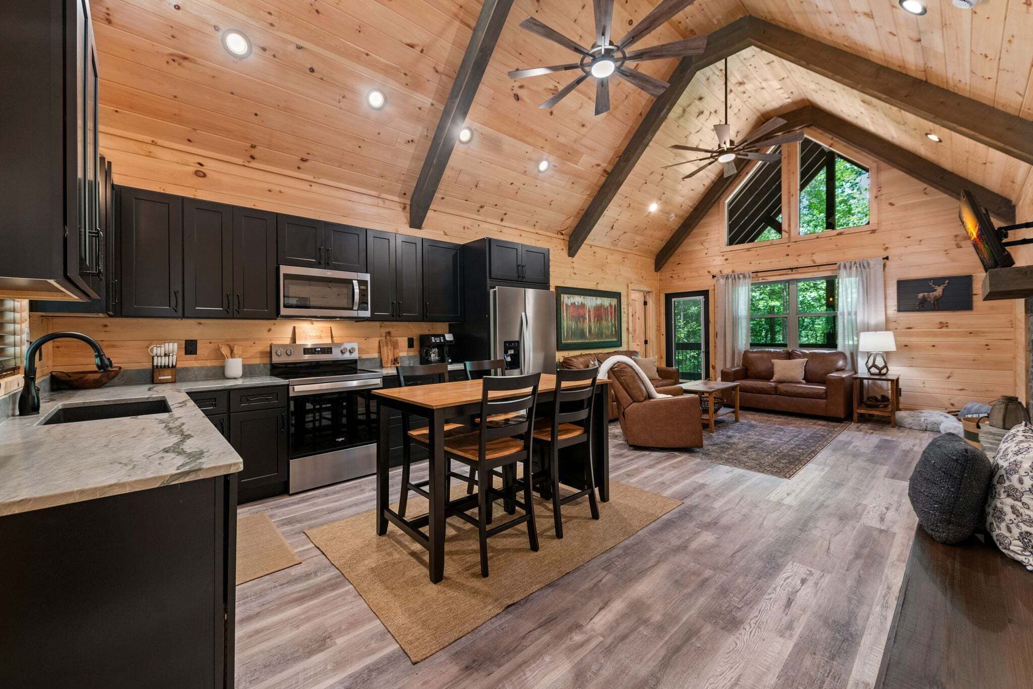 A wooden cabin interior with a kitchen, dining area, and living room.