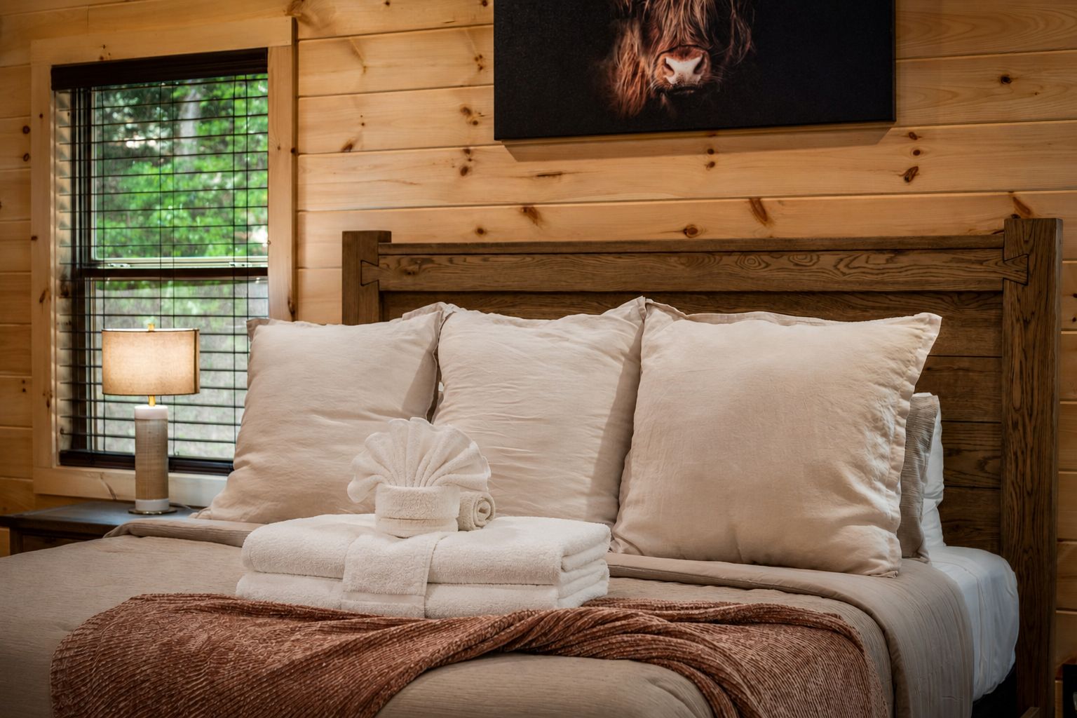 A neatly made bed with a headboard, a bedside lamp, and a framed picture on the wall.