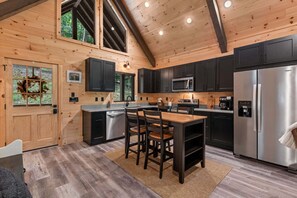 A modern kitchen with a wooden ceiling, built-in appliances, and a central island. - Let It Be Lodge - Pet Friendly | Hot Tub | Fire Pit (Mineral Bluff)
