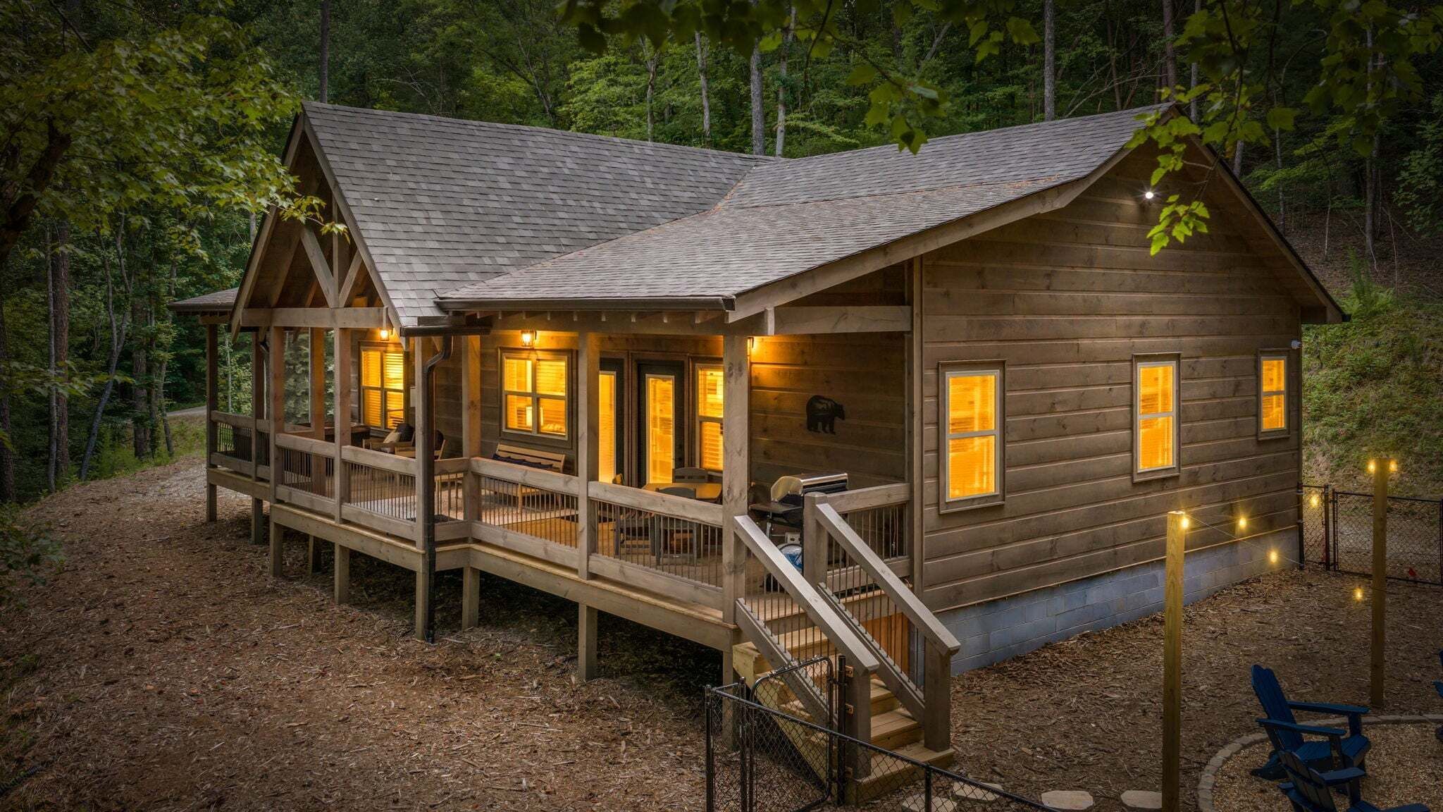 A wooden cabin with a porch, multiple windows, and a staircase leading to the entrance.