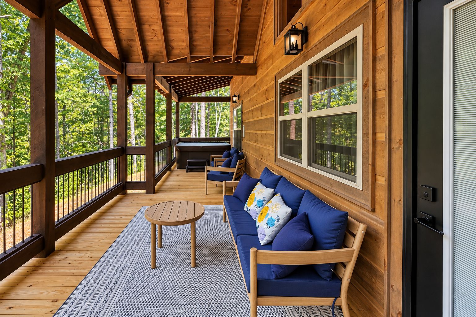 A wooden deck with a sofa and a table, surrounded by windows and a view of trees.