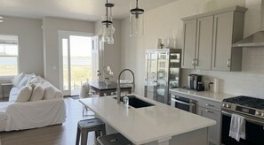 A modern kitchen with a large island, stainless steel appliances, and a view of the outdoors.