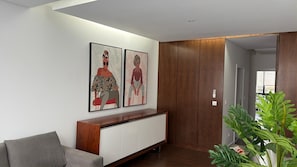 Una sala de estar moderna con un sofá gris, una consola de madera y dos obras de arte enmarcadas en la pared.
