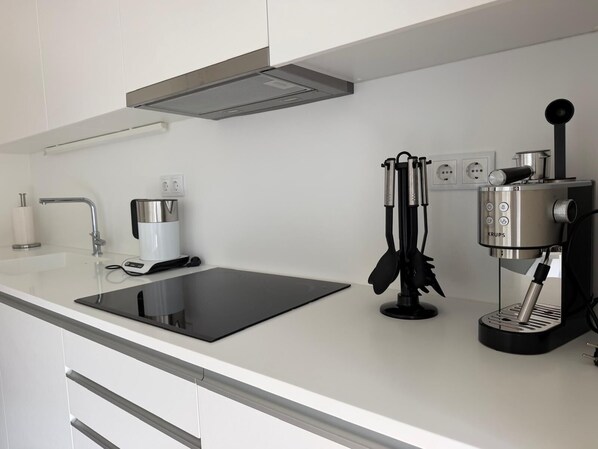 A modern kitchen with a built-in stove, a coffee machine, and a kettle. - Azores Paim 2-Bedroom Apartment 21 (Ponta Delgada)