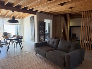 A modern living room with a sofa, dining table, and chairs. - AZORES OLD ROAD (São Roque)